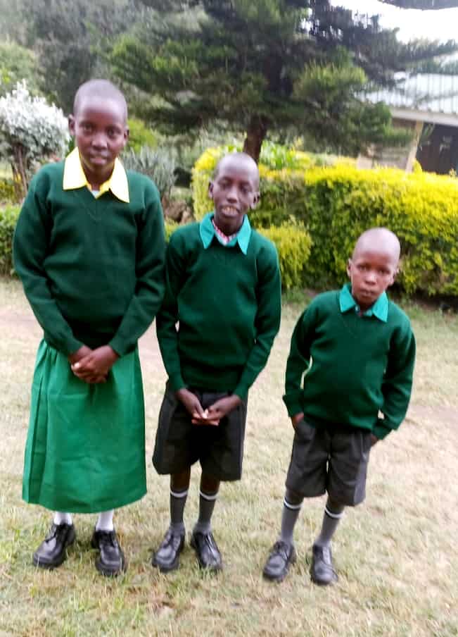 Peninah, David and Taata stand together in their school uniforms
